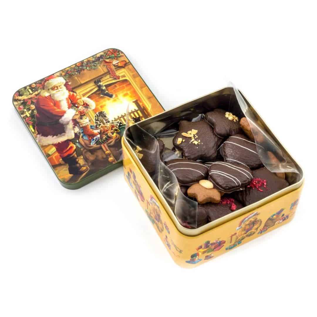 Puszka „Mikołaj” Puszka z dekorowanymi piernikami w czekoladzie deserowej z malinami, migdałami i białą czekoladą. Waga netto: 300 g wymiary: 150 x 150 mm